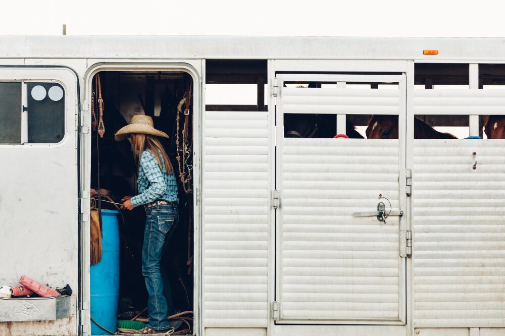 cowgirl in the tack room of a open sided horse trailer
