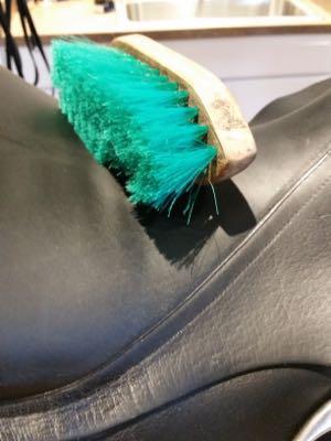 stiff brush on a black dressage saddle