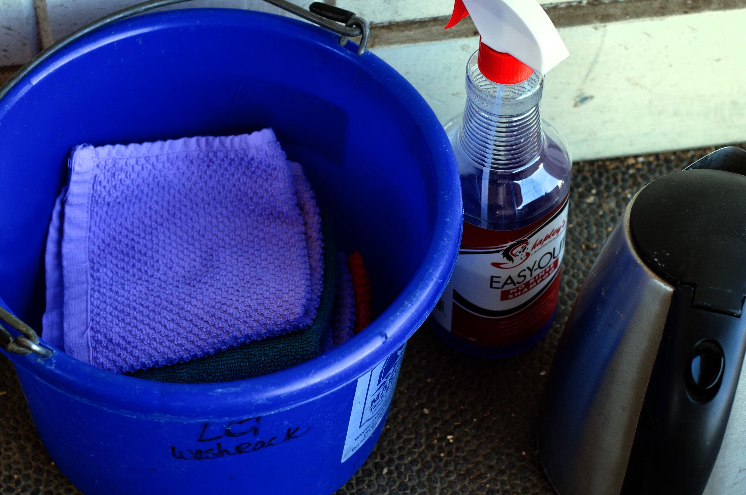 bucket with washcloths next to a hot water kettle and no rinse horse shampoo