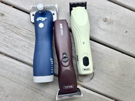 three clippers, shears, body clippers, and a cordless body clipper on a wooden surface