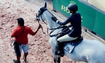 groom holding horse for the rider at an in gate