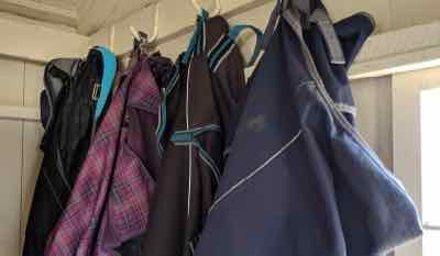 many horse blankets on hooks