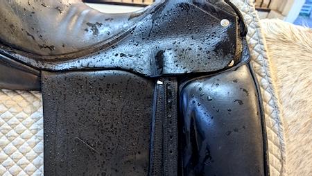 black horse saddle that is wet from the rain