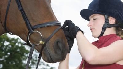 woman putting flash noseband too tight on a horse
