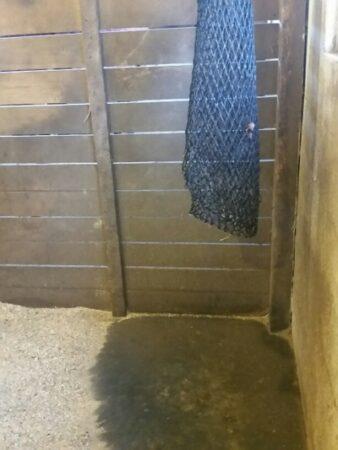 empty hay net over stall mat