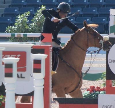 male rider beating a jumping horse with a whip