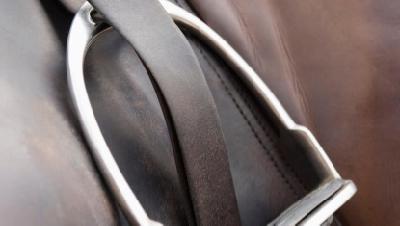 close view of stirrup on brown leather english saddle