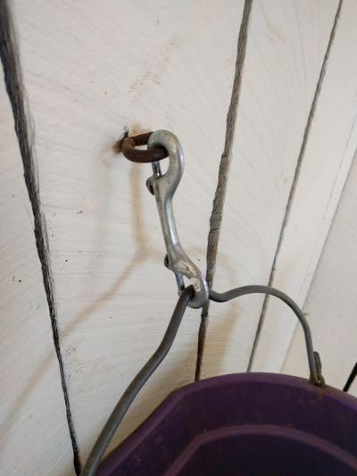horse bucket attached to wall with snap openings facing towards the wall