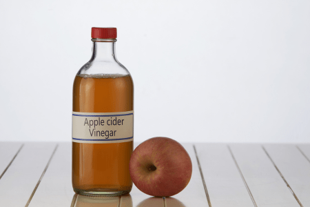 apple and bottle of vinegar on a table